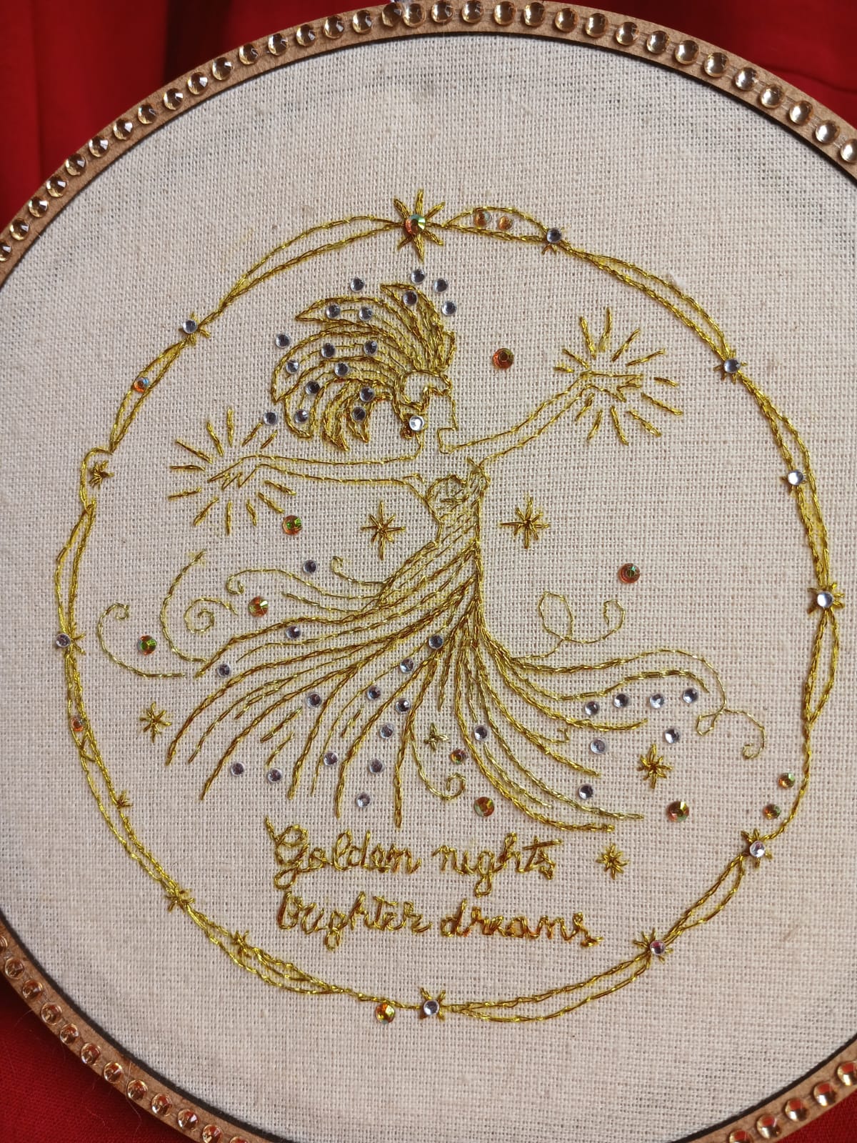 Celestial handmade embroidery with a golden figure, stars, and multicolored crystal accents on raw cotton fabric.