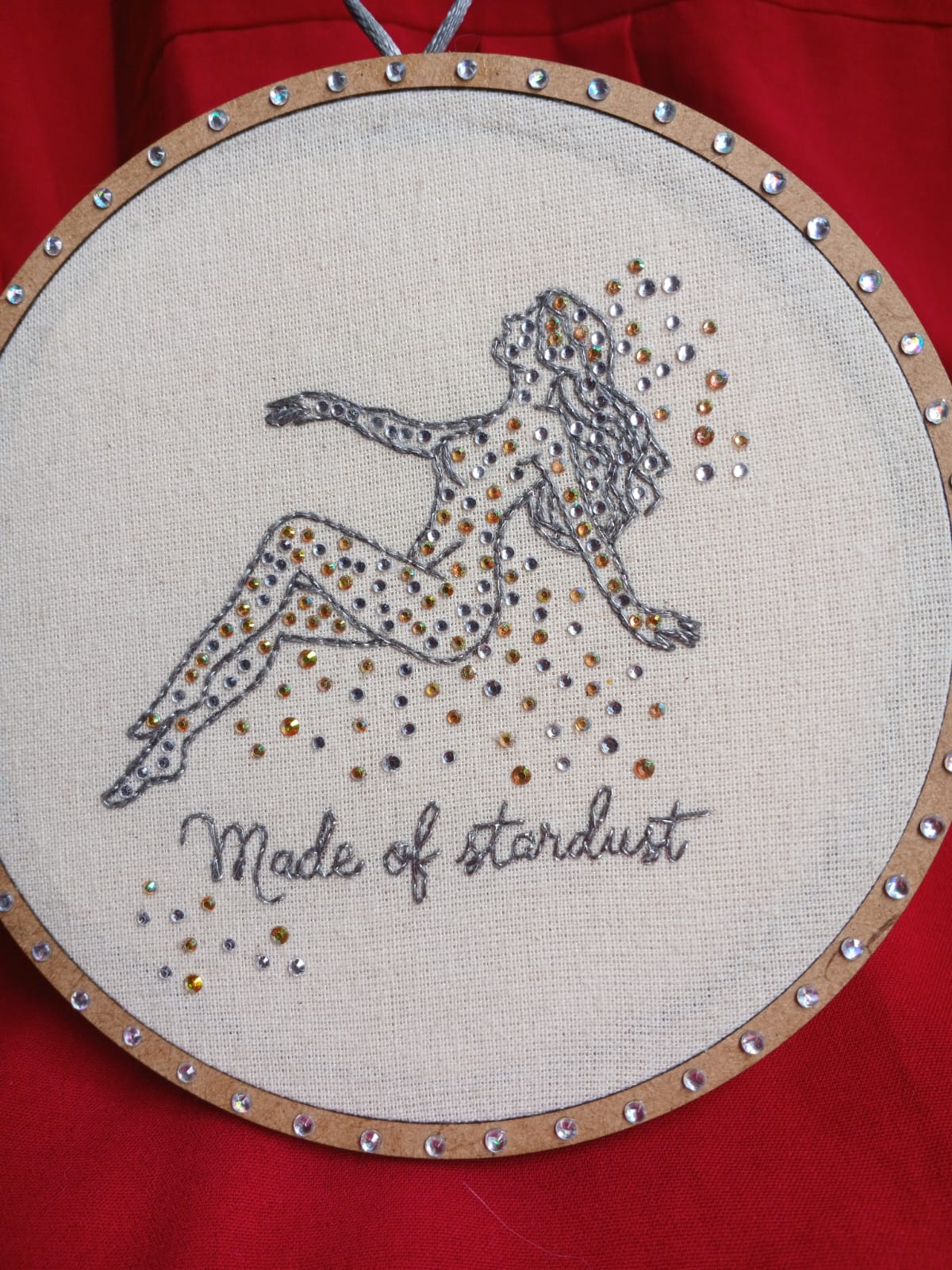 Handmade cosmic embroidery featuring a stardust figure outlined in metallic thread with gold and silver crystals.