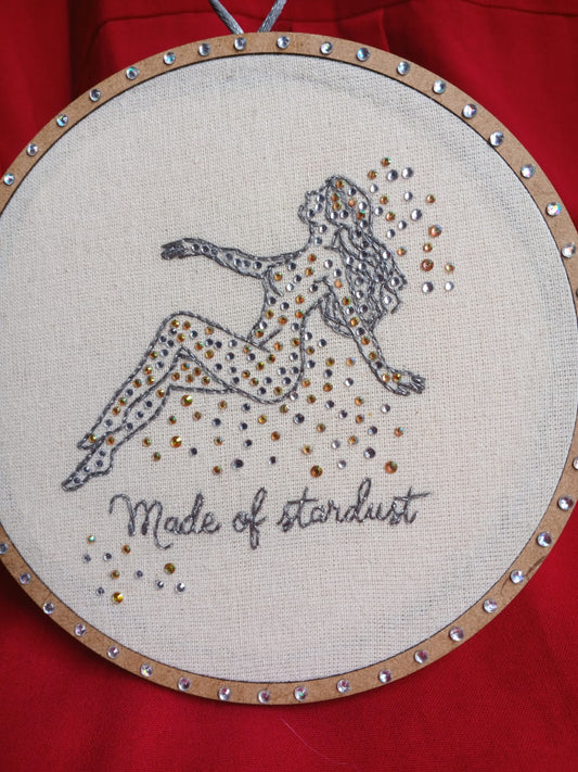 Handmade cosmic embroidery featuring a stardust figure outlined in metallic thread with gold and silver crystals.